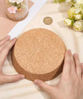 Hands holding a large cork stopper, showing the Two Pack Large Cork Stoppers For Bottles And Jars 5 To 6 Inch Tapered Wood Bottle Lids.
