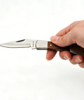 Hand holding Stainless Steel Foldable Knife With Wood Handle And Locking Blade For Hiking And Camping Ultra Portable And Easy To Carry