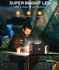 Man using Solar Powered Portable Generator Kit With 200W Peak Output And 100W Rated, 146Wh Battery, 110V AC Outlet, Includes 40W Solar Panel at a camping table with LED light modes displayed.