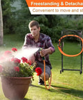 Man watering plants with Heavy Duty Freestanding Garden Hose Holder For Outdoor Use Upgraded Metal Hose Stand With Four Spikes