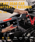 Person using 5000A Peak Jump Starter For Cars With 12V Battery Pack to start car engine, LCD display and red jumps visible