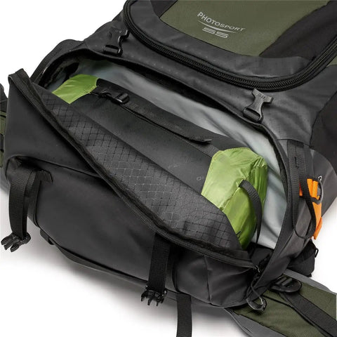PhotoSport Pro 55L AW IV Camera Backpack open showing padded compartments and green all-weather cover for DSLR and mirrorless gear.