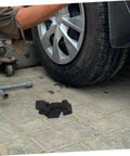 Flexible Hood Latch Lock Kit With Black T-Handle Hasps And Brackets for car engine hood use on paved ground near vehicle tire.