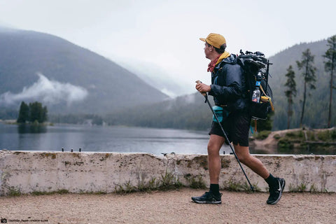 Hiker with Portable Squeeze Water Filtration System With Two 32 Oz Pouches, Straw, And Hydration Pack Adapter by a lake