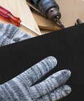 Hand in striped glove holding a black wet dry sanding sheet from the Twenty Pack Of Premium Wet Dry Sanding Sheets 11x9 Inch Assortment.