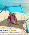 Couple sitting under a 10 X 10 Ft Beach Canopy Sun Shelter With UPF50 Plus UV Protection on a sandy beach with 2 poles.