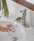 Brushed Nickel Bathroom Sink Faucet 1 Hole Single Handle Waterfall Style Brass Construction Lead Free Vanity Faucet For Home Or Commercial Use No Pop Up Drain Easy Install And Durable Design pouring water into a glass