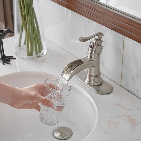 Brushed Nickel Bathroom Sink Faucet 1 Hole Single Handle Waterfall Style Brass Construction Lead Free Vanity Faucet For Home Or Commercial Use No Pop Up Drain Easy Install And Durable Design pouring water into a glass