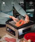 Front view of a stainless steel chamber vacuum sealer being used to seal a clear pre-cut bag with salmon.