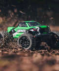 1/18 Scale Granite GROM Mega 380 Brushed 4x4 Monster Truck RTR in action on dirt, showing green body and rugged tires.