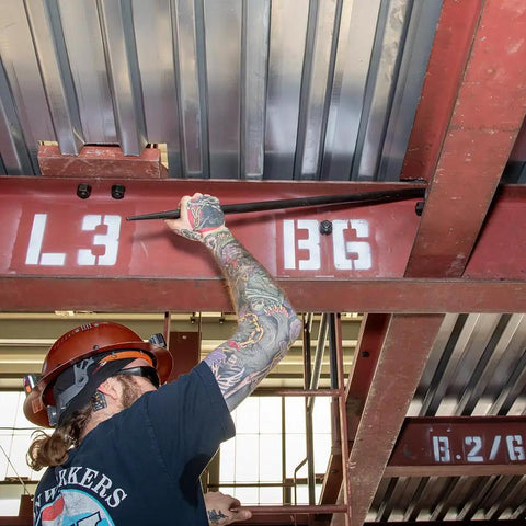Worker using Made in USA Round 7/8 Inch by 36 Inch Connecting Bar for aligning beams in construction.