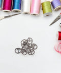 150 Pcs Miniature Alloy Buckles for Doll Clothes and DIY Projects, 5.5mm Single Prong Fasteners surrounded by sewing supplies