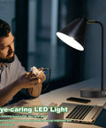 Man using 3 Way Dimmable Touch Desk Lamp With 2 USB Ports And AC Outlet for reading at night, showcasing flexible head and eye-caring light