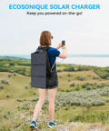 Person using phone with 30W Portable Solar Panel Charger With All In One Foldable Tri Fold Design attached to backpack in scenic field