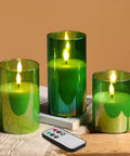 Set of 3 green glass flameless pillar candles with remote control on wooden table, showcasing realistic flicker and glow.