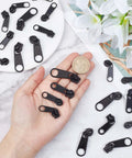 Zipper Puller Replacement Kit 32 Pieces In Four Sizes Quick Fix Zipper Slider Set displayed in hand next to a coin for scale.