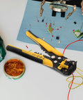 Pro Grade Automatic Self Adjusting Wire Stripper And Crimping Pliers on workspace with electronic components and tools.