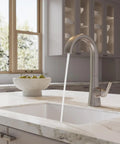 Pfister Vaneri Kitchen Faucet with Pull Down Sprayer, Stainless Steel pouring water into a sink on a marble countertop.
