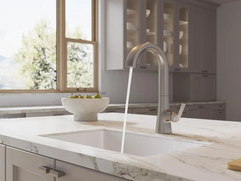 Pfister Vaneri Kitchen Faucet with Pull Down Sprayer, Stainless Steel pouring water into a sink on a marble countertop.