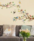 Hummingbird On Tree Branch Wall Sticker Set With Green Leaf And Flying Bird DIY Vinyl Wall Decal above a gray couch with bird pillows.