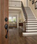 Single Cylinder Handleset With Siena Knob In Aged Bronze on door, view of elegant interior with staircase