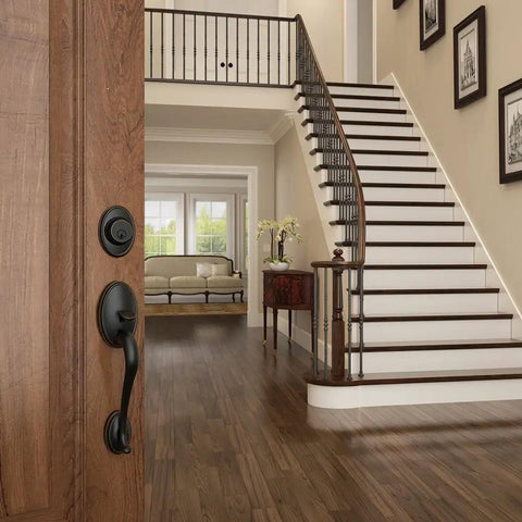 Single Cylinder Handleset With Siena Knob In Aged Bronze on door, view of elegant interior with staircase