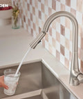 Top Shelf Pulldown Kitchen Faucet In Slick Spot Resist Stainless Steel pouring water into a glass at a kitchen sink.