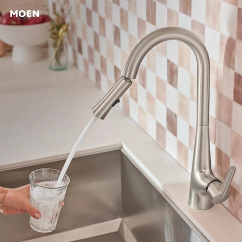 Top Shelf Pulldown Kitchen Faucet In Slick Spot Resist Stainless Steel pouring water into a glass at a kitchen sink.