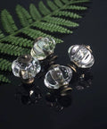 Four clear acrylic pumpkin cabinet knobs with metal bases displayed against a dark background with greenery, showcasing vintage style.
