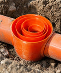 Heavy Duty Steel Electrical Conduit Pipe Connector Locking Coupler For Outdoor Junction Boxes Weather Sealed Power Runs Rock Solid build with orange pipe in dirt.