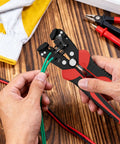 Person using Self Adjusting Wire Stripper 3 In 1 Automatic Tool For 9-20 AWG Cables on green wire on a wooden table