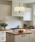Modern kitchen with white cabinetry and a central island, illuminated by a round white pendant light above the countertop.