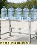 Heavy Duty Stainless Steel Workbench With Beefy Reinforced Crossbars And Folded Safety Edges For Rock Solid Kitchen Prep Or Warehouse Packing Projects with water bottles on top.