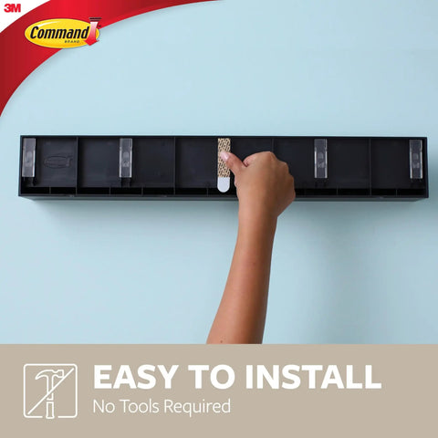 Hand installing Damage Free Picture Ledge 21 Inch Floating Shelf With Adhesive Strips No Tools Needed Holds Photos And Decorations Up To 5 Pounds Slate Finish Includes 1 Ledge And 10 Strips on wall