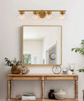 Gold Bathroom Vanity Light 28 Inch Four Light Fixture With Clear Glass Globes, hand painted above mirror in elegant room.