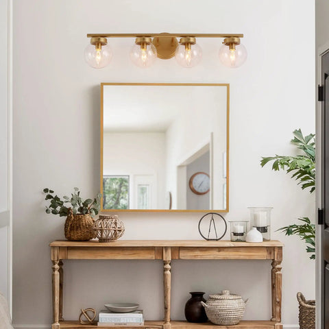 Gold Bathroom Vanity Light 28 Inch Four Light Fixture With Clear Glass Globes, hand painted above mirror in elegant room.