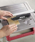 Heavy Hitter 7 Inch Wet Tile Saw With Rust Proof Stainless Top and Adjustable Rip Fence cutting ceramic tile on water tray.