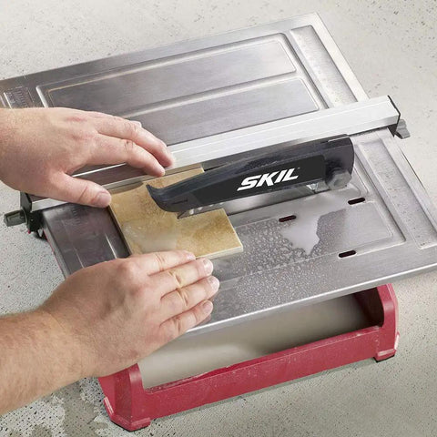 Heavy Hitter 7 Inch Wet Tile Saw With Rust Proof Stainless Top and Adjustable Rip Fence cutting ceramic tile on water tray.