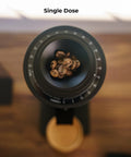 Solid Single Dose Coffee Grinder Featuring 63Mm Red Titanium Conical Burrs And Plasma Ionizer To Crush Beans Sick Flat And Eliminate Static Drama For Flawless Pulls In Sleek Black Housing with coffee beans inside.