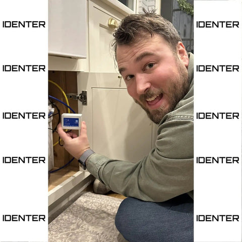Man installing Real Time Water Flow Meter For Irrigation And Garden Hose GPM Usage Monitor in a kitchen cabinet