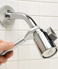 Hand using One Stop 2-In-1 Wrench For Angle Stops And Compression Couplings to adjust plumbing valve against tiled wall