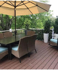 Outdoor patio with table, chairs, and umbrella; greenery background with Expandable Privacy Screen Fence For Balcony And Backyard Outdoor Faux Ivy Panel 16 By 45 Inches Closed Expands To 92 Inches Wide With FSC Certified Willow Frame And Decorative Ivy Leaves And Flowers Low Maintenance Easy To Clean.