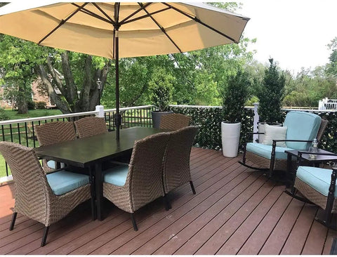 Outdoor patio with table, chairs, and umbrella; greenery background with Expandable Privacy Screen Fence For Balcony And Backyard Outdoor Faux Ivy Panel 16 By 45 Inches Closed Expands To 92 Inches Wide With FSC Certified Willow Frame And Decorative Ivy Leaves And Flowers Low Maintenance Easy To Clean.