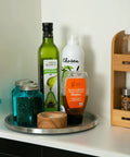 Slick Brushed Stainless Steel Lazy Susan Turntable with olive oil, honey, and jars in a pantry, 10.5 inches wide.