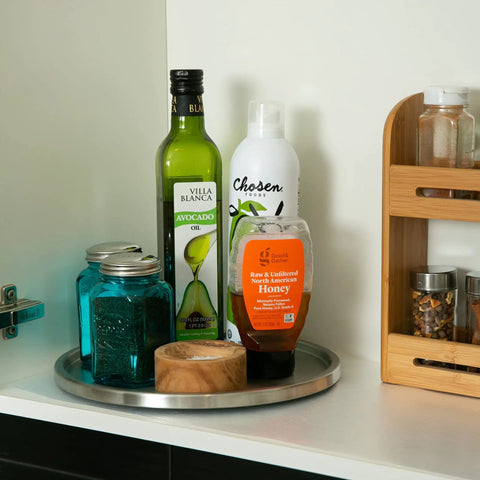 Slick Brushed Stainless Steel Lazy Susan Turntable with olive oil, honey, and jars in a pantry, 10.5 inches wide.