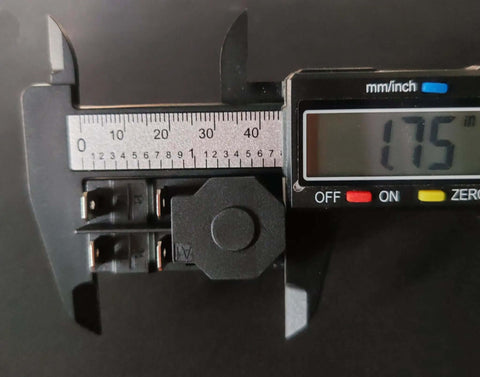 Close-up of a 4-pin electromagnetic pushbutton switch with caliper measurement, part of the Electromagnetic Pushbutton Switch Set, 4 Pin, 1/2 HP, Double Pole, 16A At 120V, Compatible With 120V And 220V Systems, Heavy Duty Starter Buttons For Garden Tools And Power Machinery, 2 Pack.