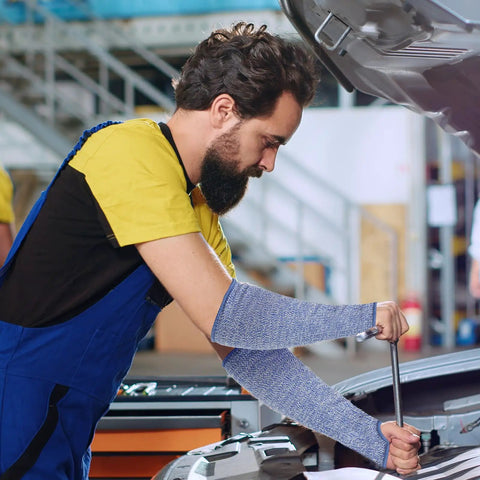 Level 5 Cut Resistant Arm Sleeves With Thumb Hole, Tough As Nails HPPE Forearm Guards For Kitchen And Workshop, Real Deal Slash Shield For Sensitive Skin, 1 Pair Blue Small worn by a man while working on a car.