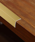 Top Tier Matte Gold L Shaped Corner Guards Peel And Stick Molding Trim For Furniture Edge Bumper on wooden tabletop.