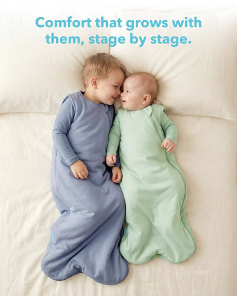 Two babies lying on a bed wearing Soft Breathable Viscose Bamboo Sleep Sack For Babies 6 12 18 Months One TOG Wearable Blanket in blue and green.