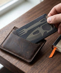 Hand holding 4 In 1 Pocket Multi Tool Card Stainless Steel Outdoor Survival Gear with fork, bottle opener, and ruler beside wallet.